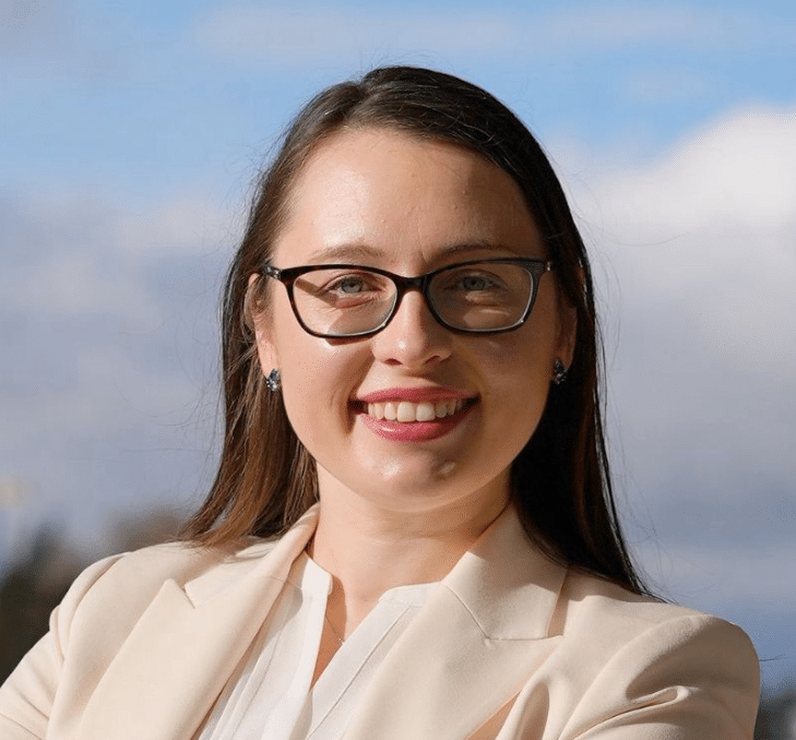 Professional headshot of a smiling fractional executive with glasses in a cream blazer