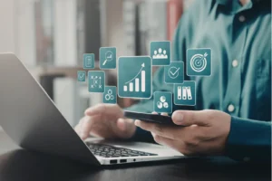 Professional using phone and laptop with floating digital icons representing marketing tools and data