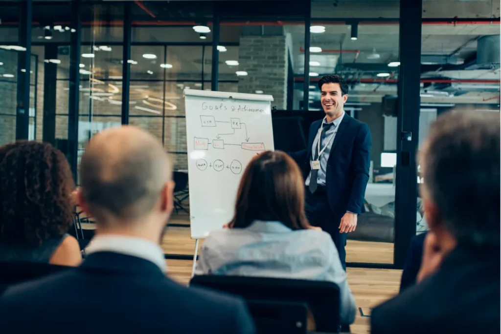 Marketing speaker presenting strategy to an audience in front of a whiteboard