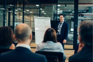 Marketing speaker presenting strategy to an audience in front of a whiteboard