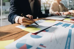Business analyst reviewing colorful charts and reports on a wooden desk